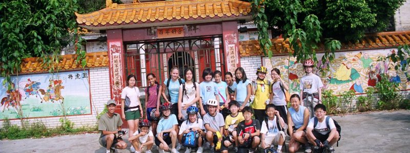 Students in a group shot on a day of cycling in front of a temple